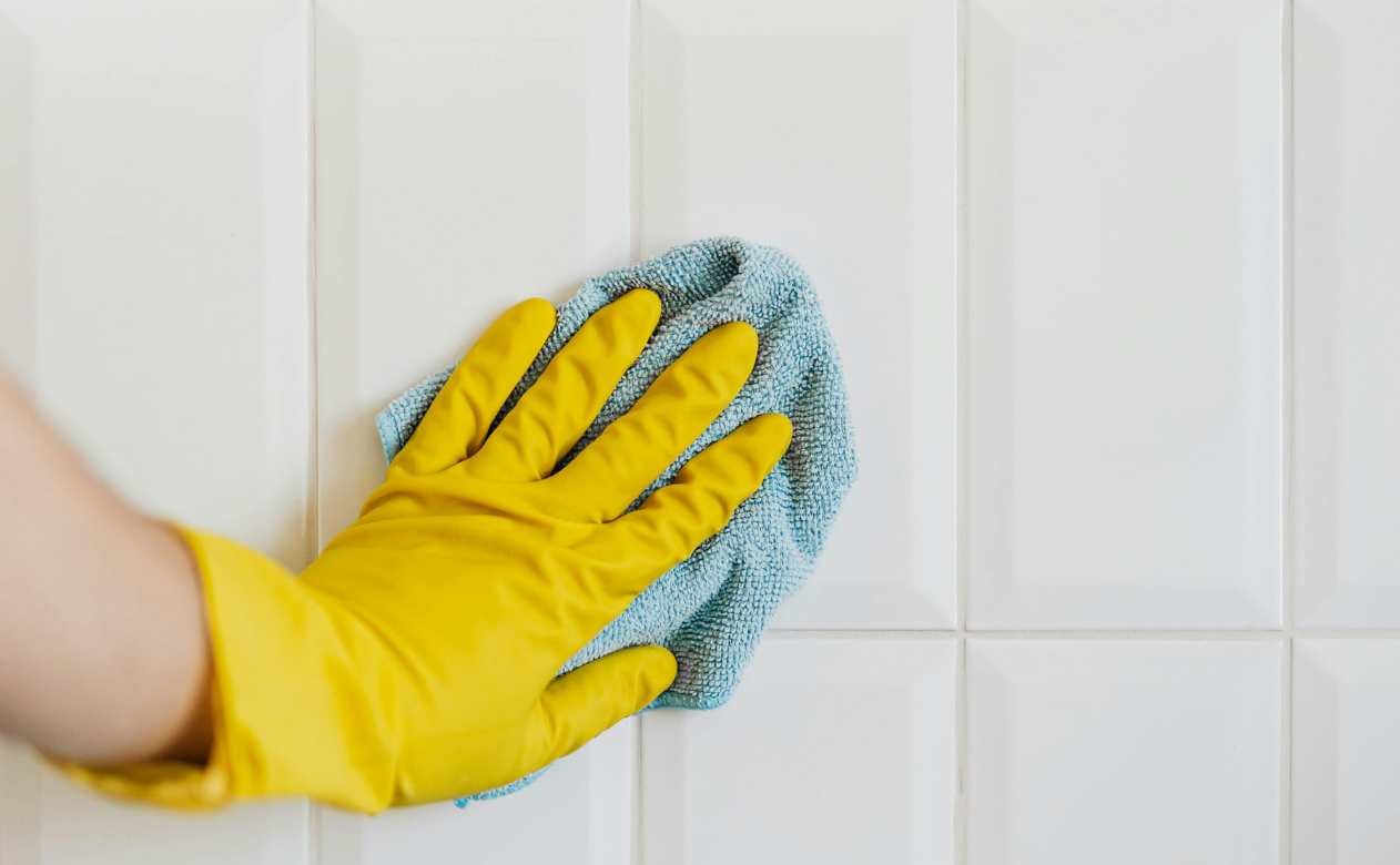 image of hand cleaning white tile backsplash
